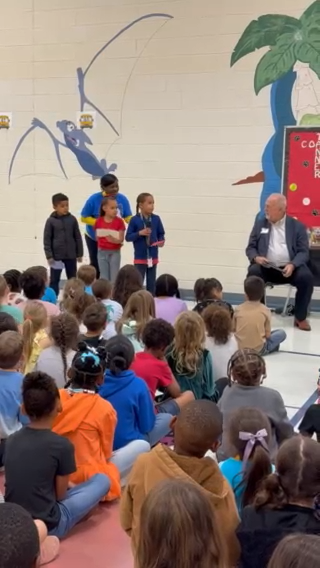 A group of people and a man in front of an audience of students