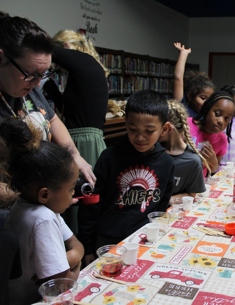 Student watch as Ms. McIntire measures juice 