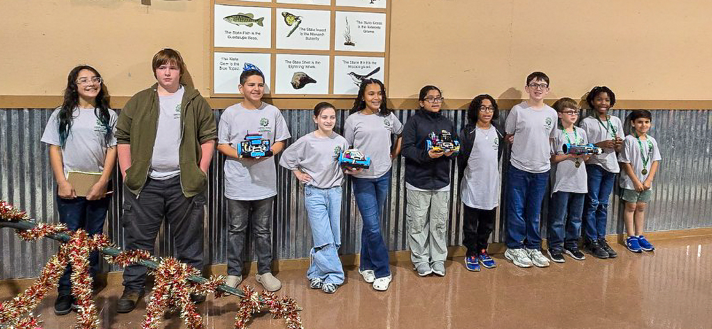 A group of students holding awards in front of a wall