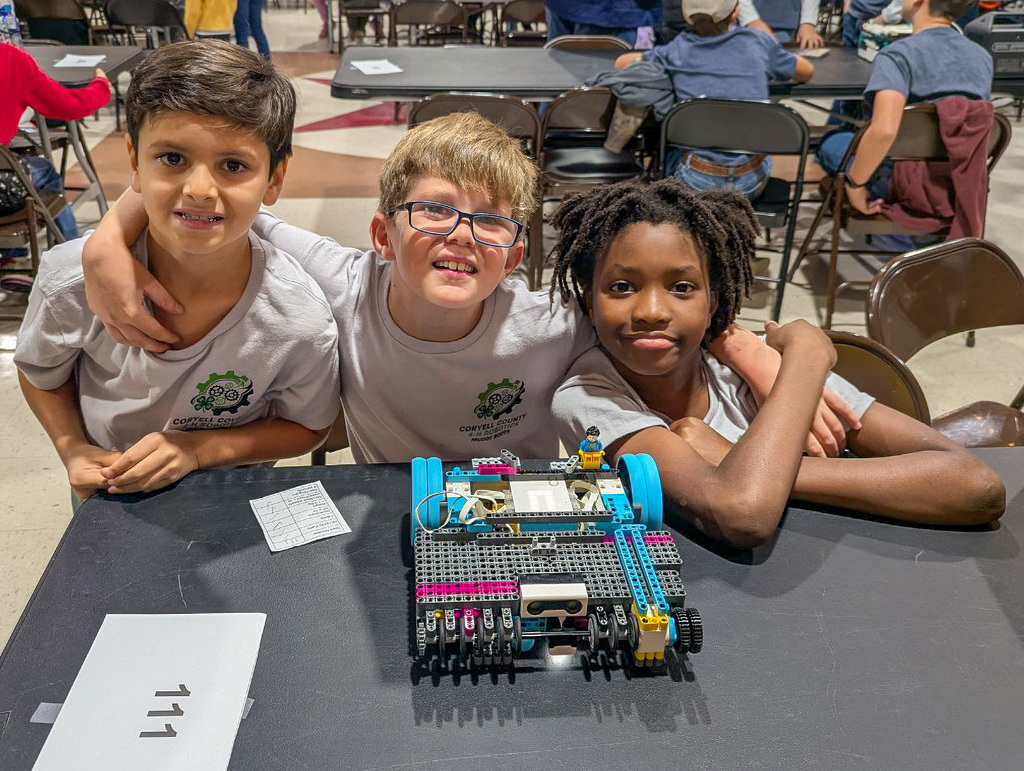 A group of students smiling behind their robot
