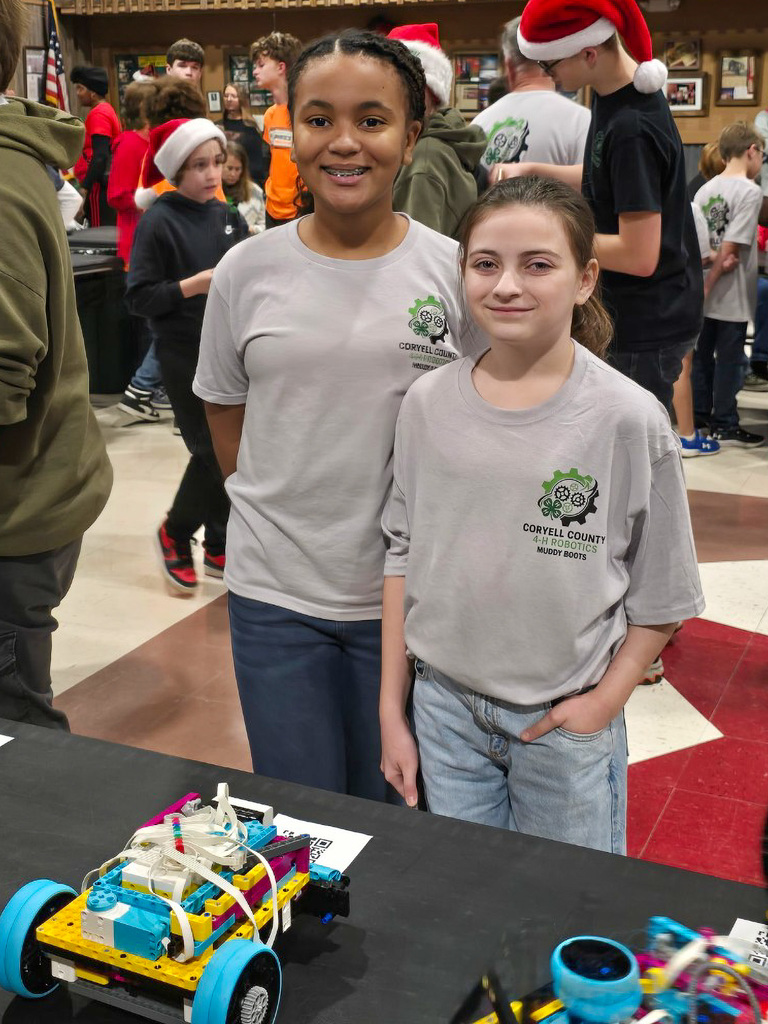 Two students smiling behind their robot