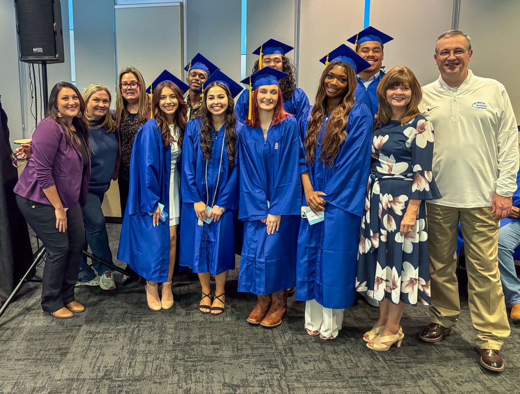 A group of students in caps and gowns with a group of teachers