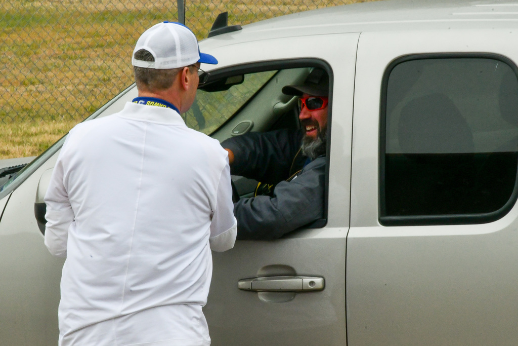 A man in a truck smiling as another hands him a box
