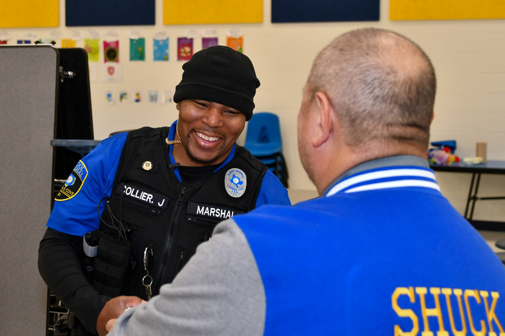 A man smiling as another hands him a box