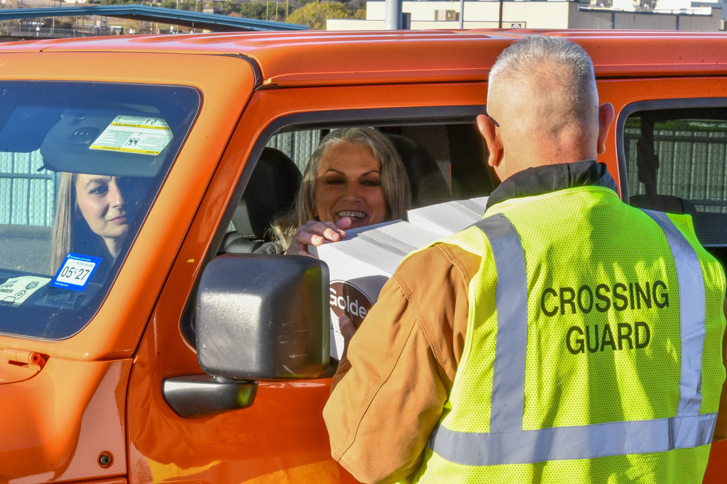 A woman in a car smiling as she's handed a box