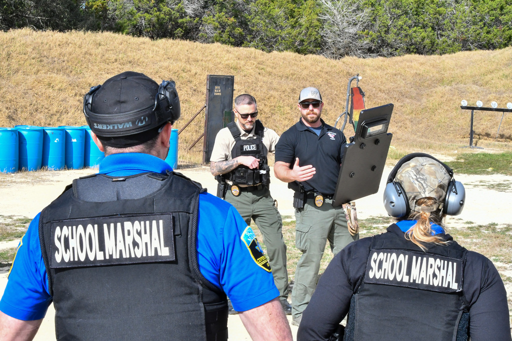 Two police officers demonstrating how to use a shield