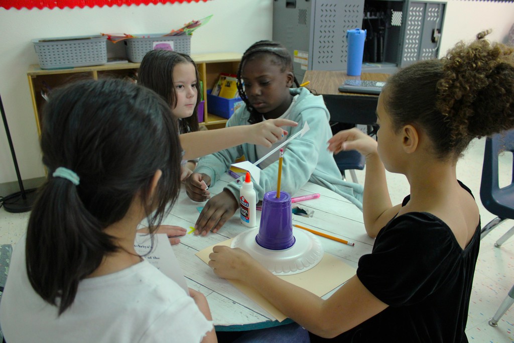 Students work at table building weather vanes