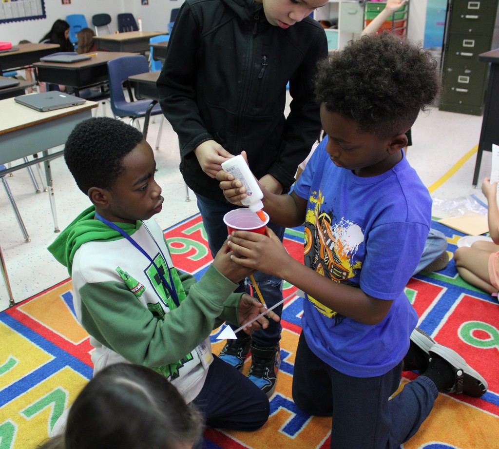 Students work together to glue base of their weather vane