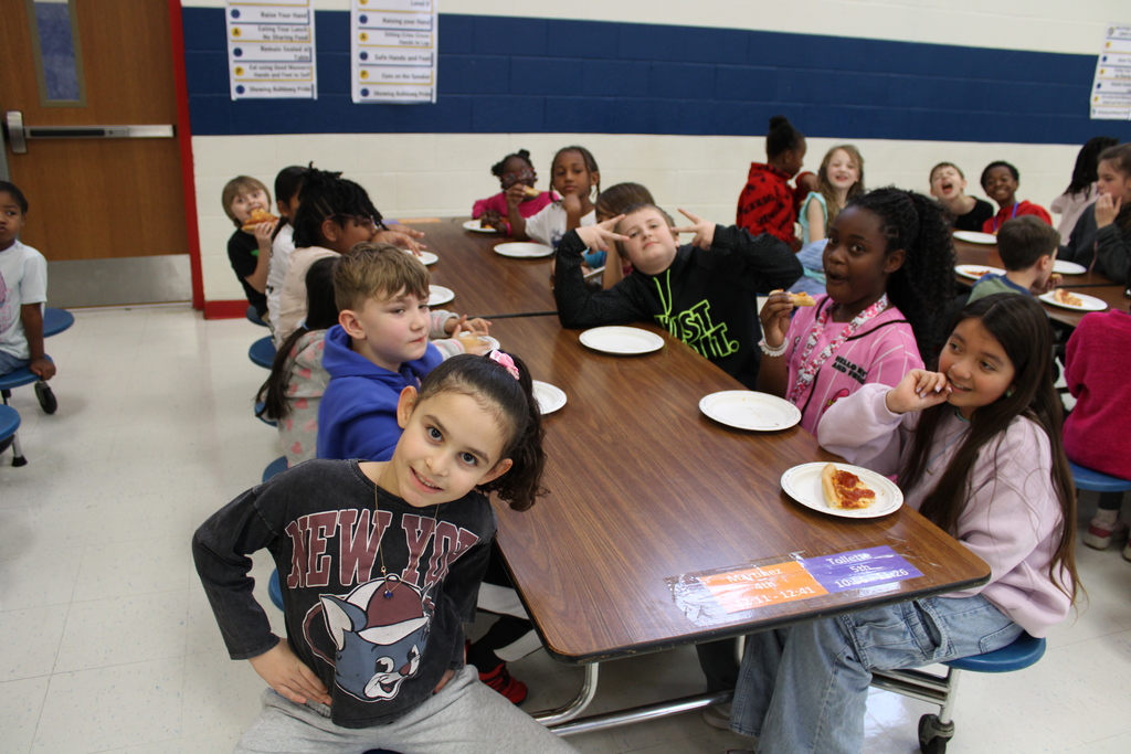 Students pose with pizza at table