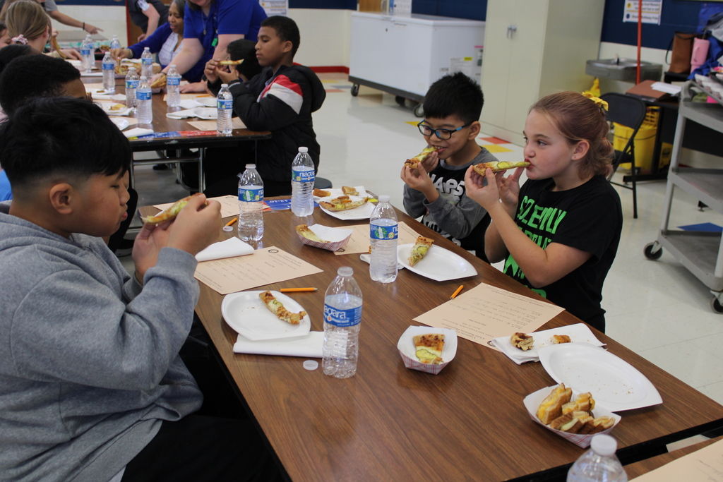 Students try food at table with rating sheet