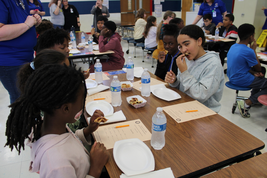 Students try food at table with rating sheet
