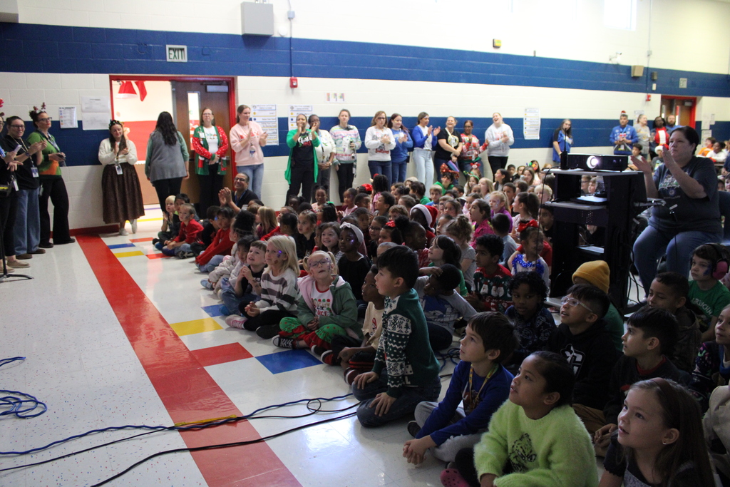 Kids sitting on floor of cafeteria singing