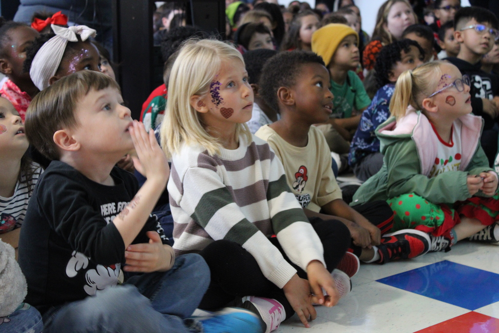 Kids sitting on floor of cafeteria singing
