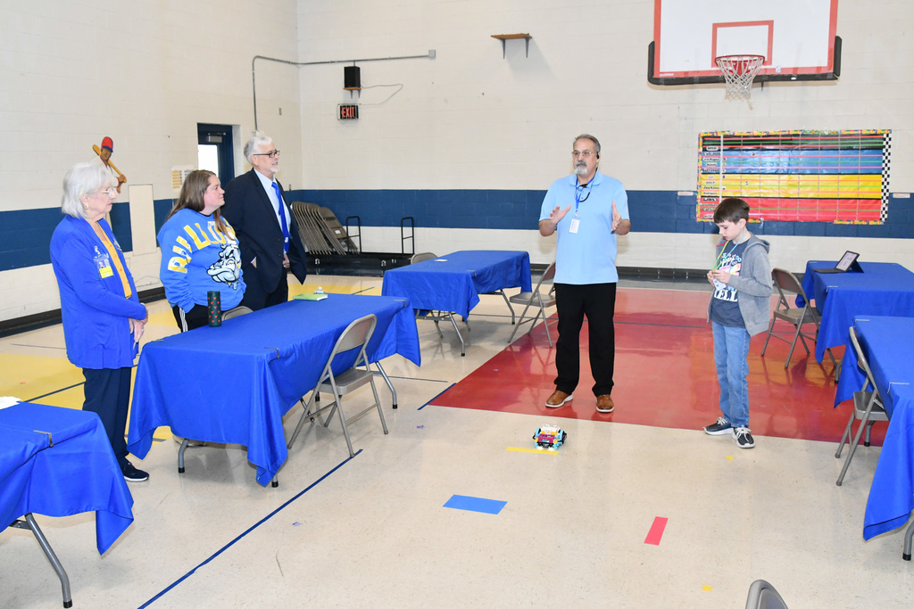 A group of adults and a student with a lego robot