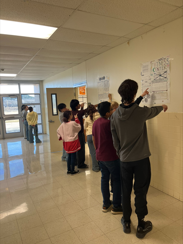 Students pointing at posters on the school hall walls. 