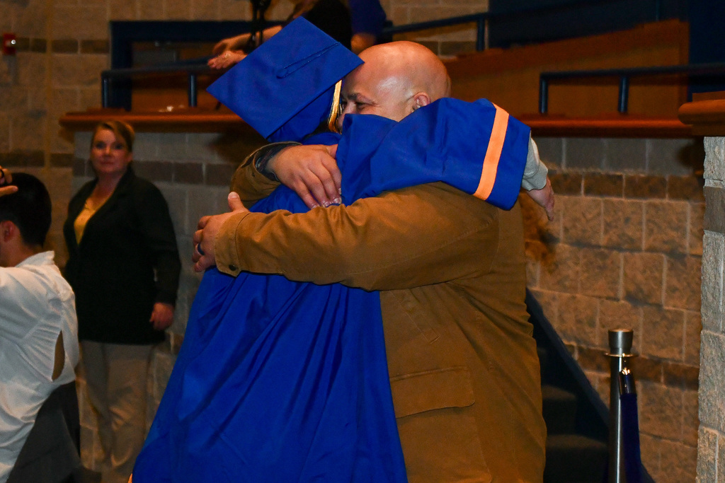 Student and educator hugging in celebration at graduation