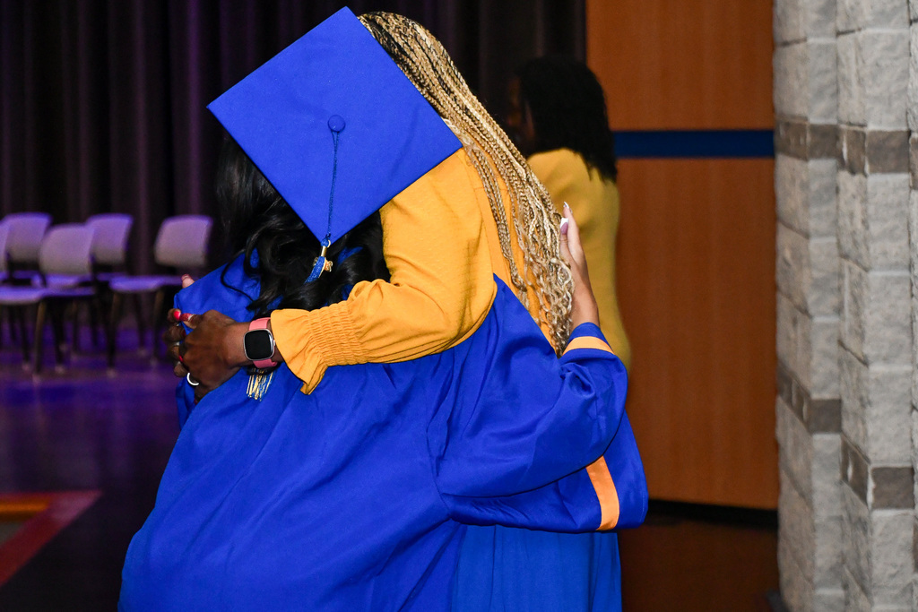 Student and educator hugging in celebration at graduation