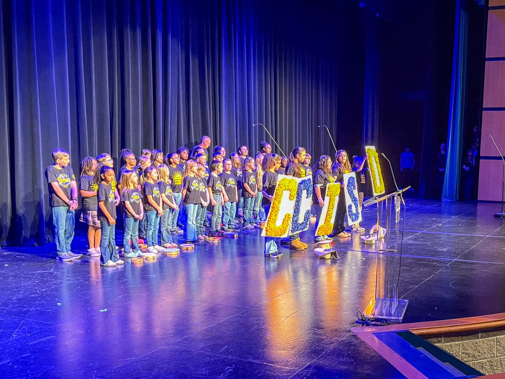 A group of students singing and holding signs