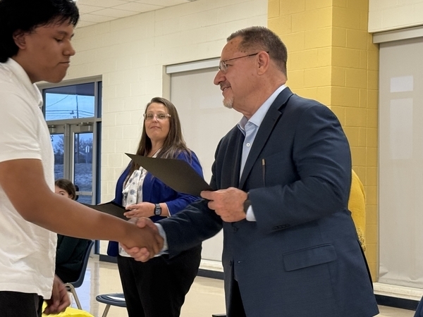 Principal Grammer shaking hands with a student.
