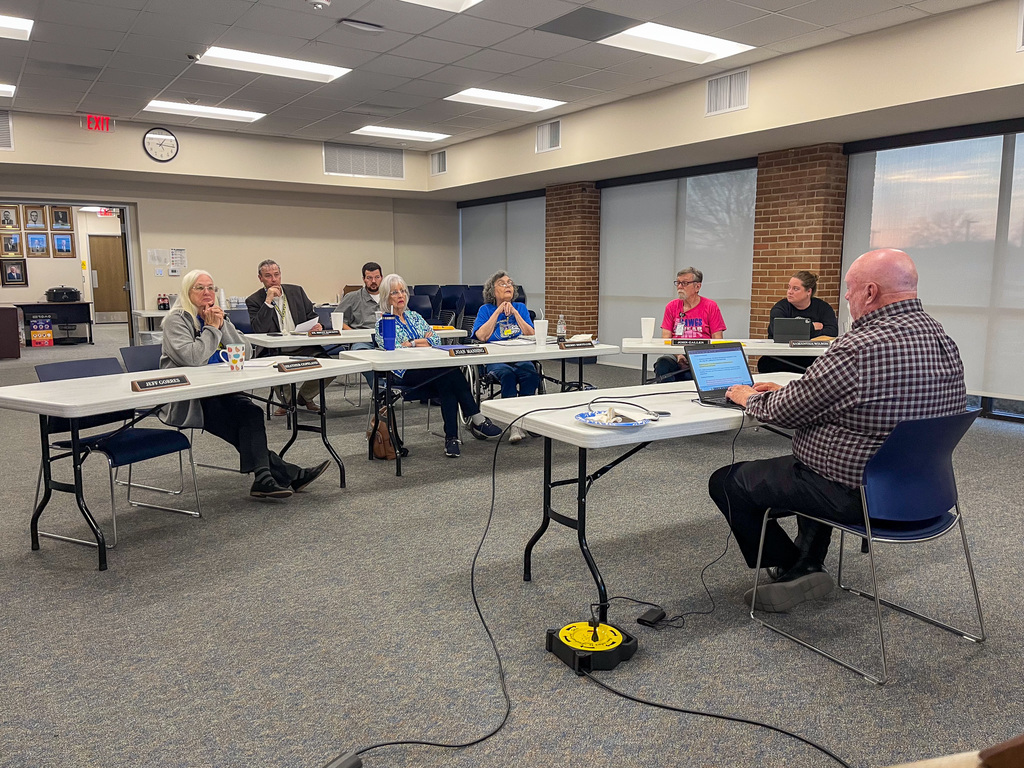 A group of adults seated at tables in a board room