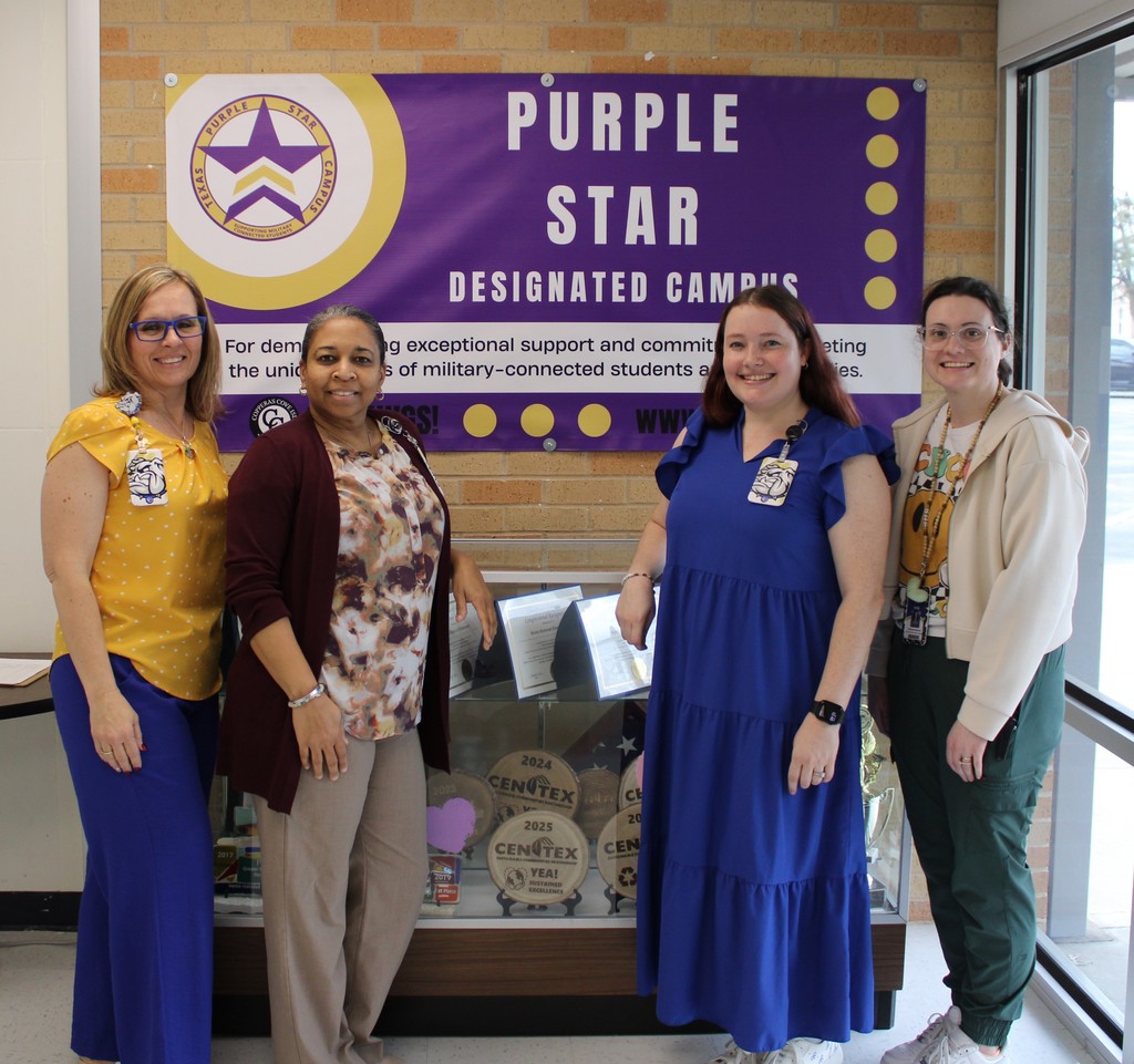 HHE admin pose in front of mounted purple star banner