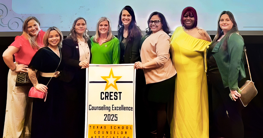 A group of smiling counselors holding a banner