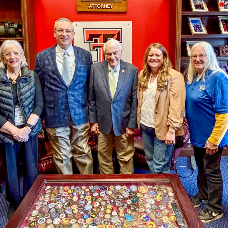 A group of smiling adults behind a table with challenge coins