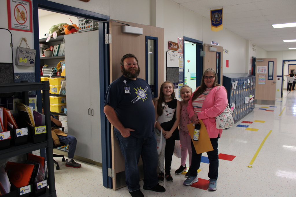 Parents and staff pose in the hallway while visiting