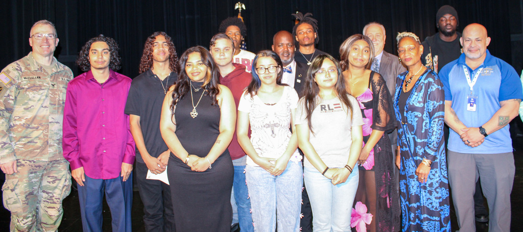 A group of students and adults smiling and holding awards