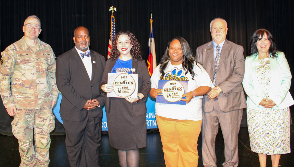 A group of students and adults smiling and holding awards