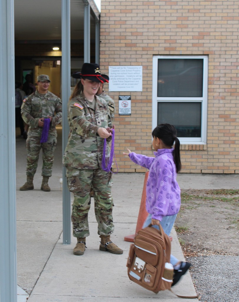 Soldiers hand out beads to students in the morning for purple up day