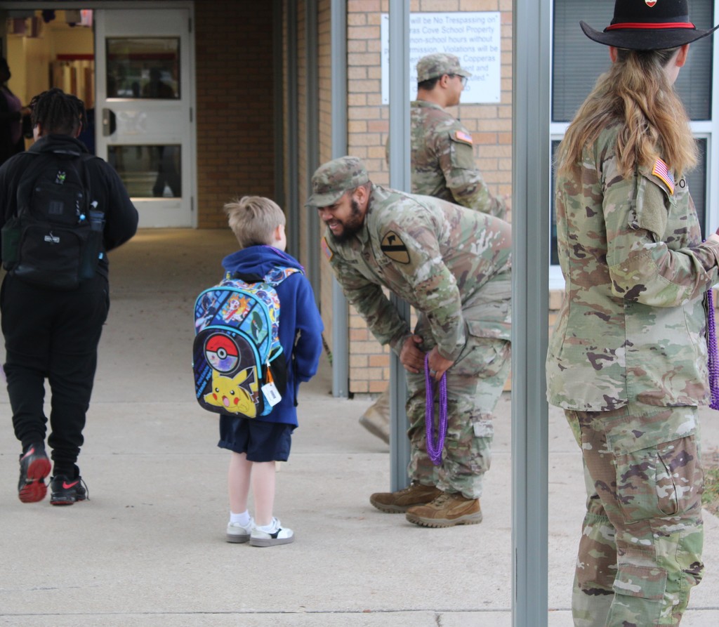 Soldiers hand out beads to students in the morning for purple up day