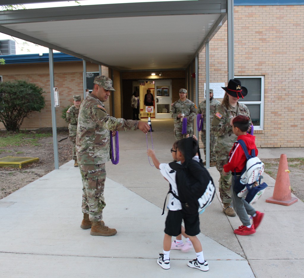 Soldiers hand out beads to students in the morning for purple up day