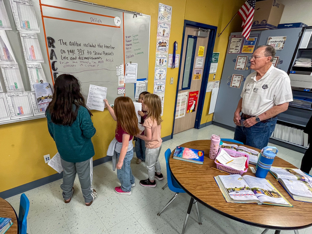 Students doing a reading activity while adults watch on