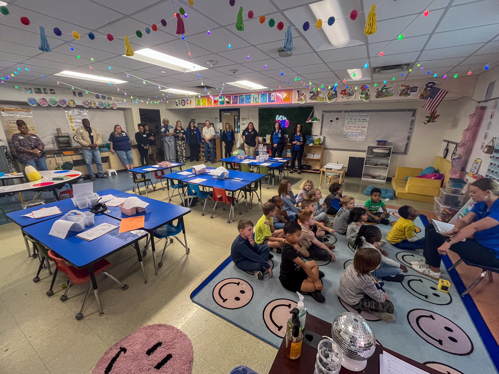 Students doing a reading activity while adults watch on