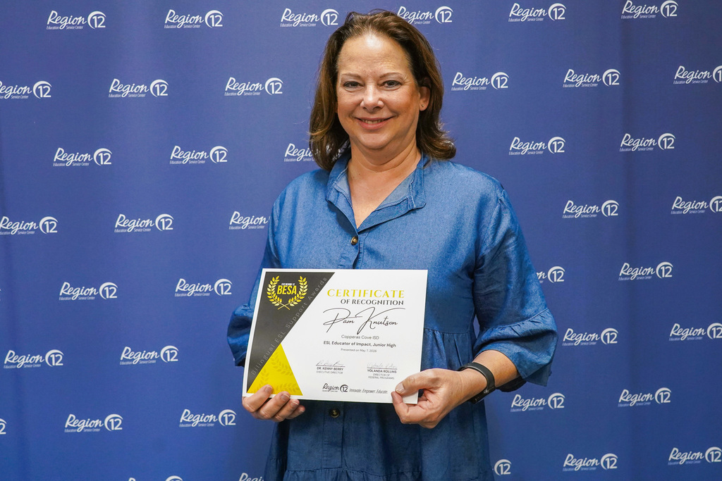Woman holding an award, smiling in front of a backdrop