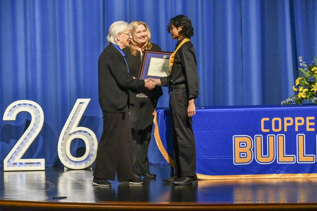Student shaking hands with school board president, receiving award