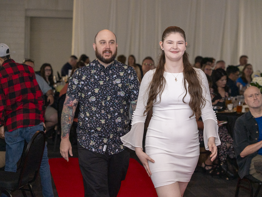 Student and a teacher walking down a carpet at a banquet
