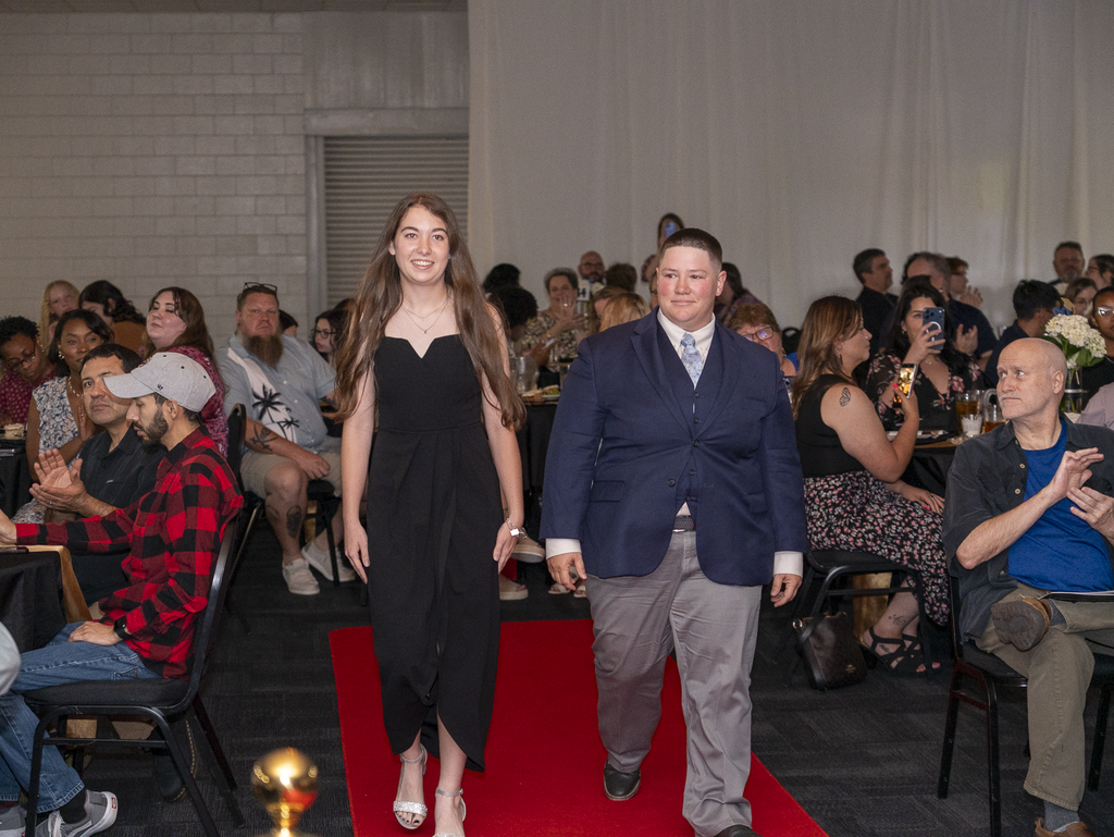 Student and a teacher walking down a carpet at a banquet