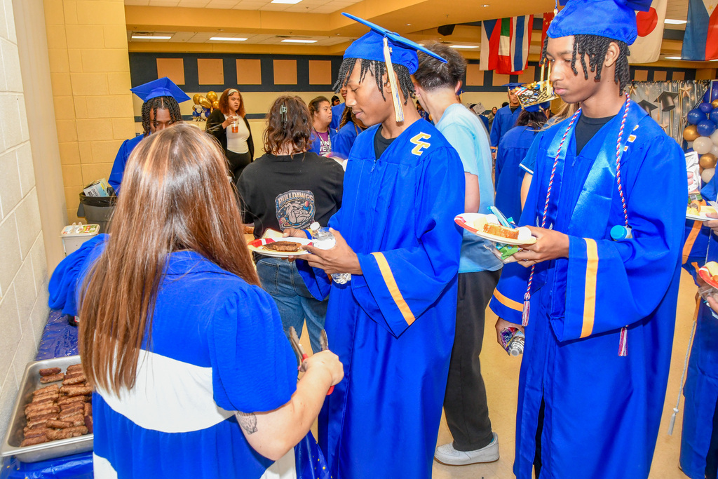 Student with a plate of pancakes on a stage and a teacher serving