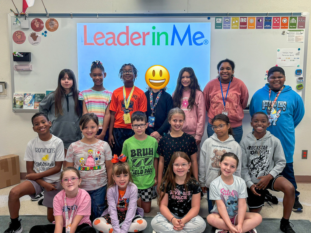 A group of smiling students in front of a white board