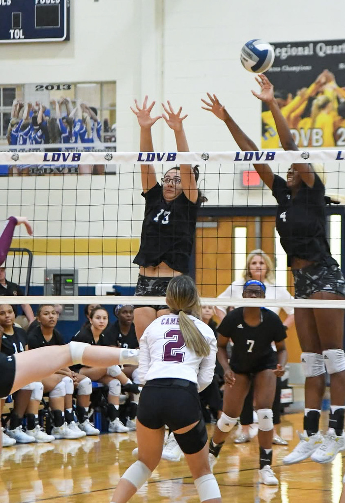 Volleyball players blocking at net