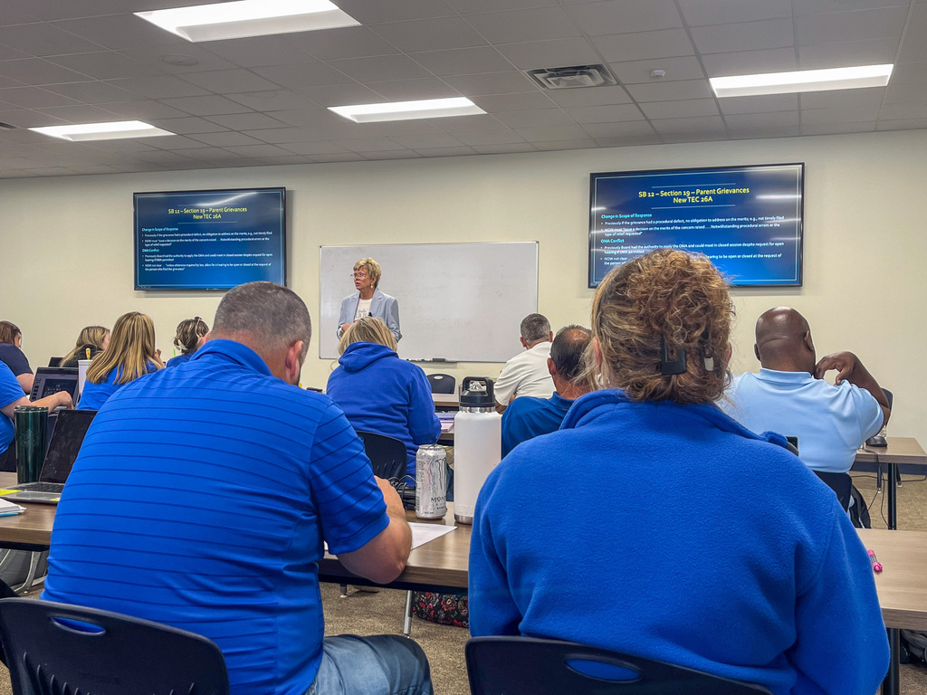 A woman speaking to a crowd in a training room