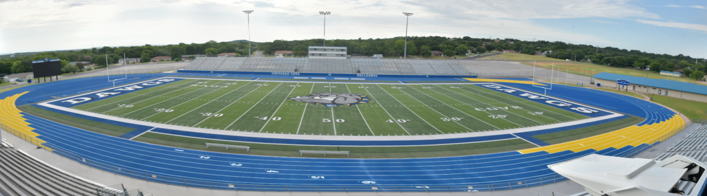 Blue and gold track surrounding a turf field in a stadium