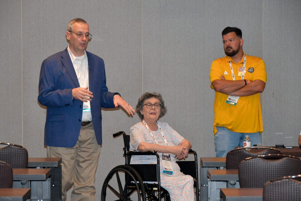 Three adults talking at the front of a hotel ballroom