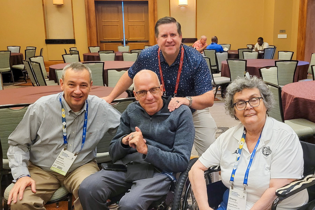 Four adults smiling in a hotel ballroom