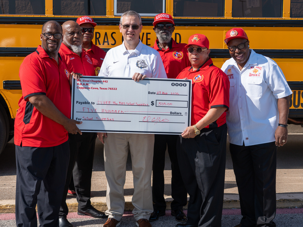 A group of people in front of a school bus smiling