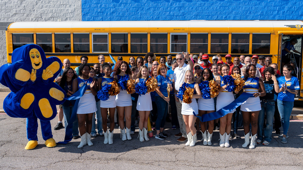 A group of people in front of a school bus smiling