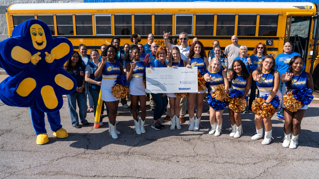 A group of people in front of a school bus smiling