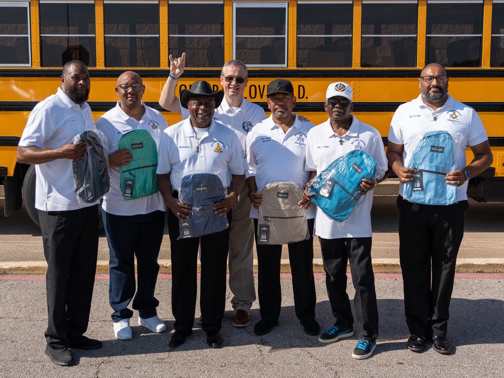 A group of people in front of a school bus smiling